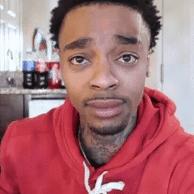 a man wearing a red hoodie is looking at the camera .