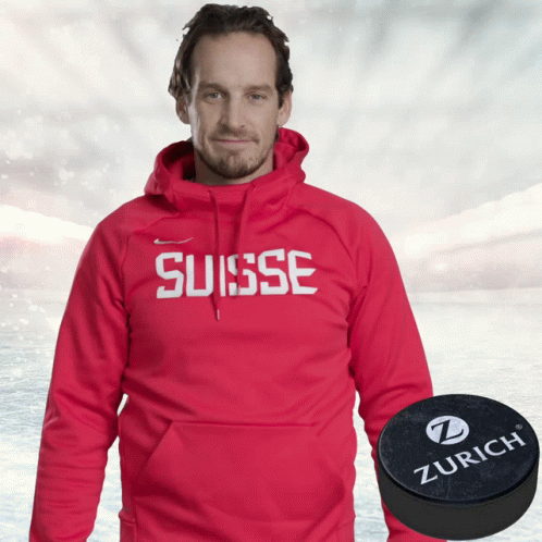 A Man Wearing A Red Hoodie That Says Suisse Next To A Zurich Puck GIF