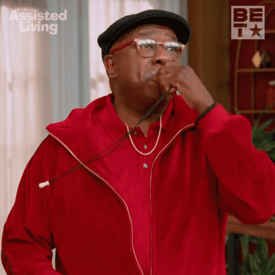 A Man Wearing A Red Jacket And A Black Hat With Assisted Living On The Bottom Right GIF