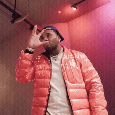 A Man Wearing A Red Jacket And A Blue Hat Making A Peace Sign GIF