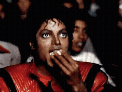 A Man Wearing A Red Jacket Is Covering His Mouth With His Hand GIF
