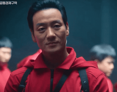 A Man Wearing A Red Jacket With A Black Strap Around His Neck GIF