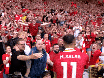 A Man Wearing A Red Jersey With The Number 11 On It Stands In Front Of A Crowd GIF