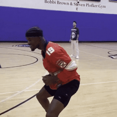 A Man Wearing A Red Jersey With The Number 19 On It Is Jumping On A Basketball Court GIF