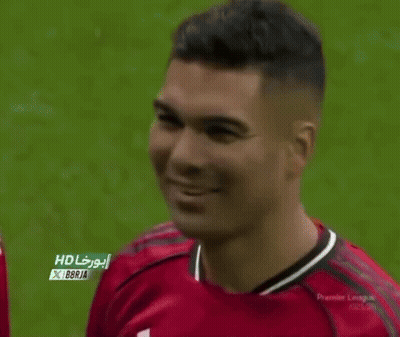 A Man Wearing A Red Manchester United Jersey Is Smiling On A Soccer Field . GIF