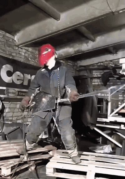 A Man Wearing A Red Mask Is Welding In Front Of A Sign That Says Cern GIF