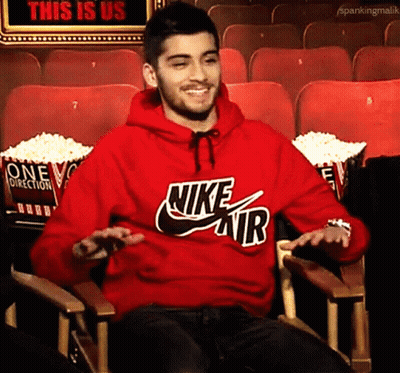 A Man Wearing A Red Nike Air Hoodie Is Sitting In A Theater GIF