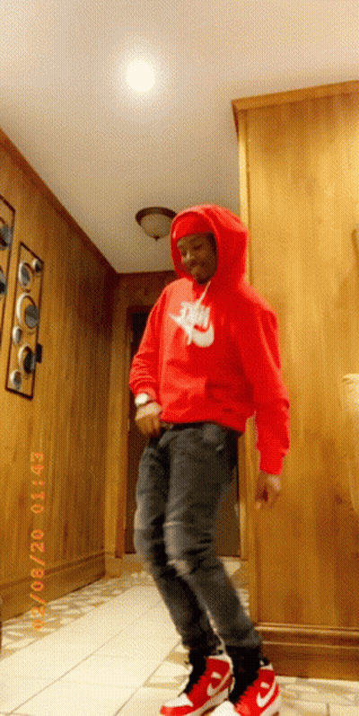 A Man Wearing A Red Nike Hoodie Is Standing In A Hallway GIF