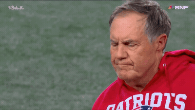 A Man Wearing A Red Patriots Sweatshirt Stands On A Football Field GIF