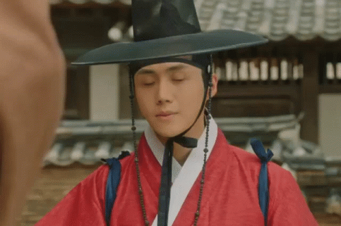 A Man Wearing A Red Robe And A Black Hat . GIF