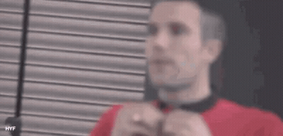 A Man Wearing A Red Shirt And A Black Tie Is Adjusting His Tie . GIF