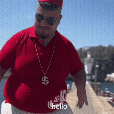 A Man Wearing A Red Shirt And A Dollar Sign Necklace Is Saying Hello GIF