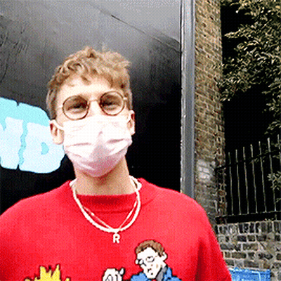 A Man Wearing A Red Shirt And A Mask With The Letter R On His Neck GIF