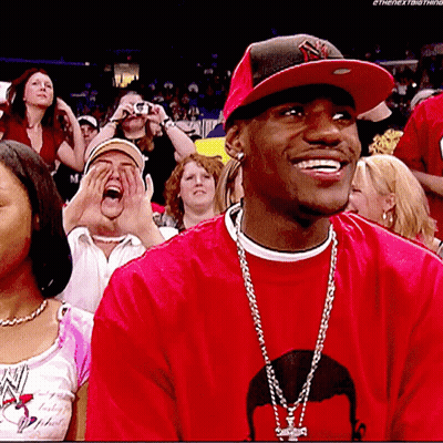 A Man Wearing A Red Shirt And A Ny Hat Is Smiling In A Crowd GIF