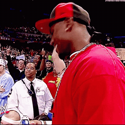 A Man Wearing A Red Shirt And A Red Hat Is Standing In Front Of A Crowd .. GIF