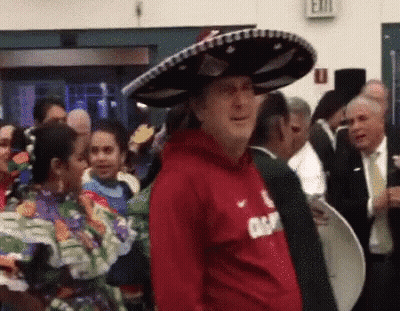 A Man Wearing A Red Shirt And A Sombrero Is Standing In A Crowd . GIF