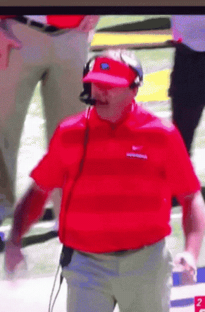 A Man Wearing A Red Shirt And A Visor Is Standing On A Football Field GIF