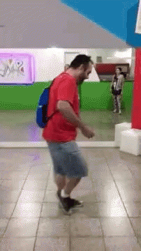 A Man Wearing A Red Shirt And Blue Backpack Is Dancing GIF