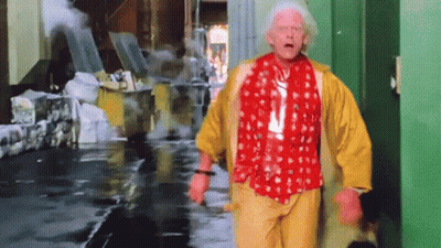 A Man Wearing A Red Shirt And Yellow Pants Is Walking Down A Street GIF