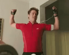A Man Wearing A Red Shirt Is Flexing His Muscles GIF