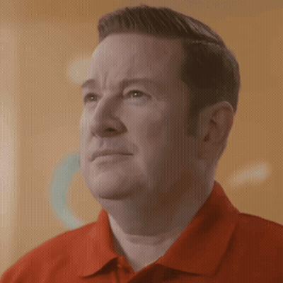 A Man Wearing A Red Shirt Is Looking At Something GIF
