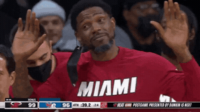 A Man Wearing A Red Shirt That Says Miami Is Waving His Hands In The Air . GIF
