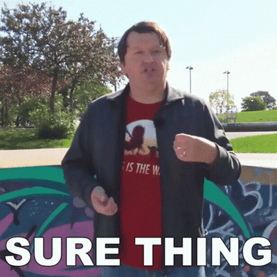 A Man Wearing A Red Shirt That Says " Sure Thing " Stands In Front Of A Graffiti Wall GIF