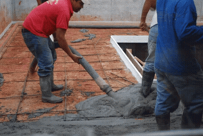 A Man Wearing A Red Shirt That Says ' Texas ' On It Pours Concrete GIF