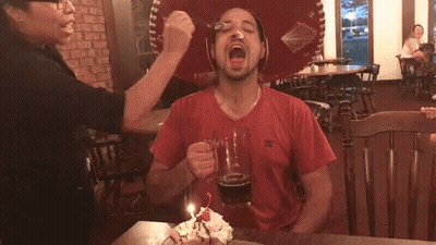 A Man Wearing A Red Shirt With A Dc Logo On The Front GIF