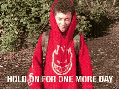 A Man Wearing A Red Spitfire Hoodie Is Standing In A Forest GIF