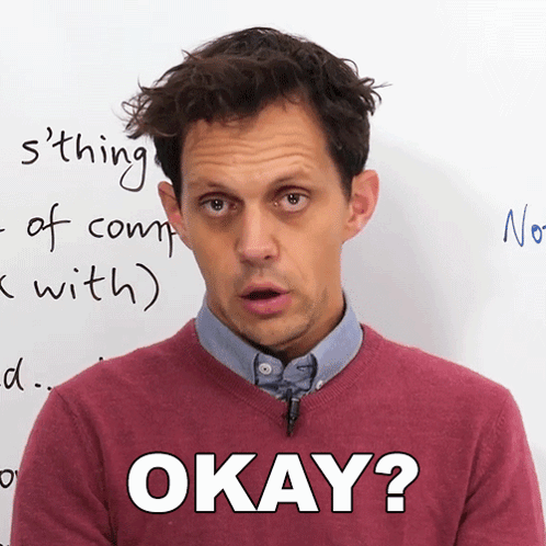 A Man Wearing A Red Sweater Says Okay In Front Of A White Board GIF