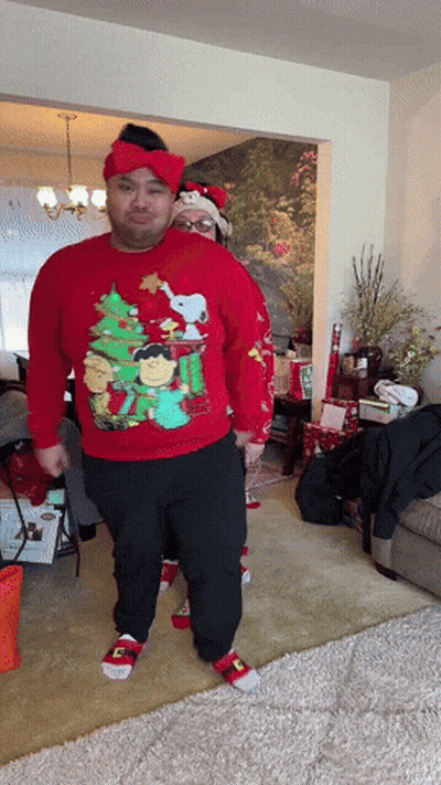 a man wearing a red sweater with a christmas tree and snoopy on it