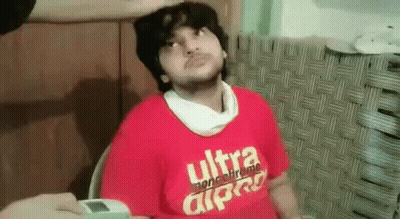 A Man Wearing A Red T-Shirt With The Word Ultra On It Is Sitting In A Chair . GIF