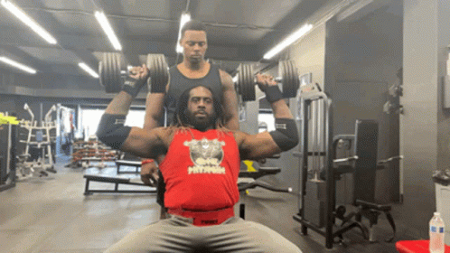 A Man Wearing A Red Tank Top That Says Twist Is Lifting Dumbbells In A Gym GIF