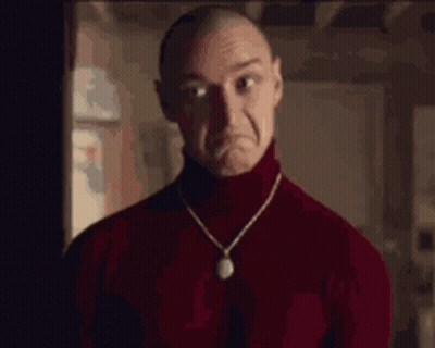 A Man Wearing A Red Turtleneck Sweater And A Necklace Is Making A Sad Face . GIF