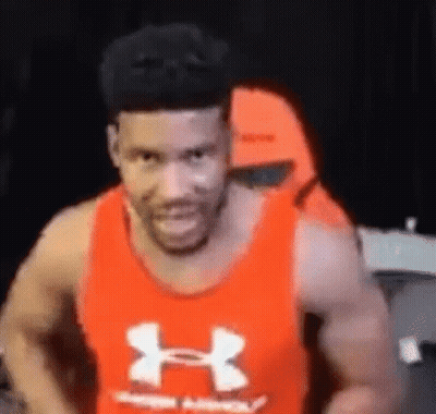 A Man Wearing A Red Under Armour Tank Top Is Smiling And Looking At The Camera . GIF