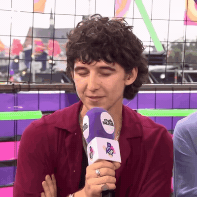 A Man Wearing A Ring Is Holding A Microphone With The Word Muse On It GIF