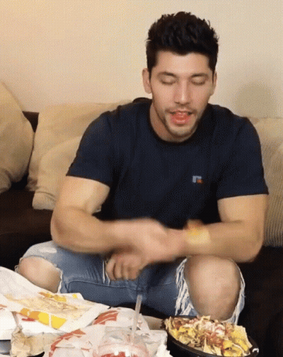 A Man Wearing A Russell T-Shirt Is Sitting On A Couch Eating Chips GIF