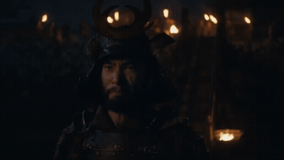 A Man Wearing A Samurai Helmet Stands In The Dark GIF