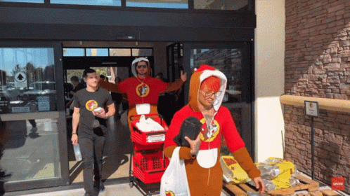 A Man Wearing A Santa Costume Is Pushing A Red Cart GIF