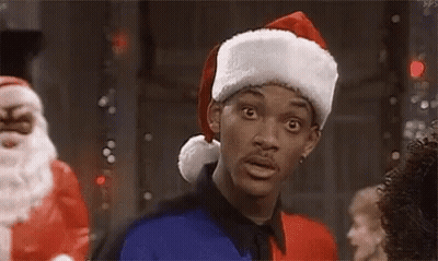 A Man Wearing A Santa Hat Is Standing In A Room . GIF