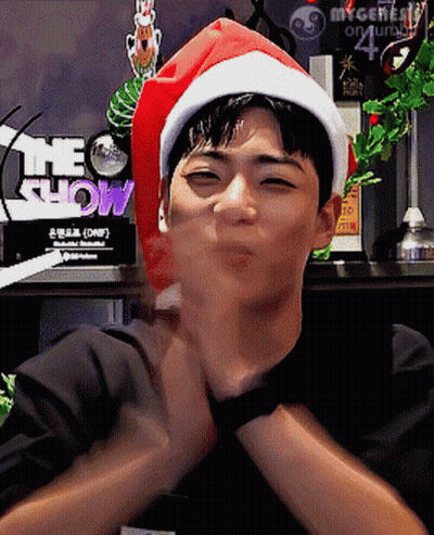 A Man Wearing A Santa Hat With The Word Show Behind Him GIF