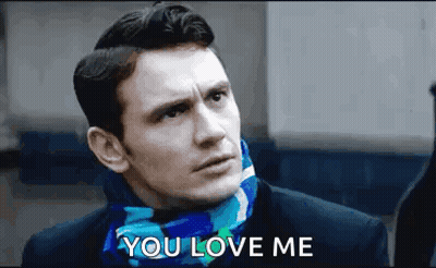 A Man Wearing A Scarf Around His Neck Is Talking To Someone . GIF