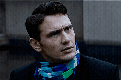 A Man Wearing A Scarf Around His Neck Looks To The Side GIF