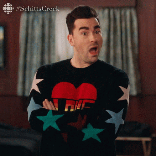 A Man Wearing A Schitts Creek Sweater With Stars On The Sleeves GIF