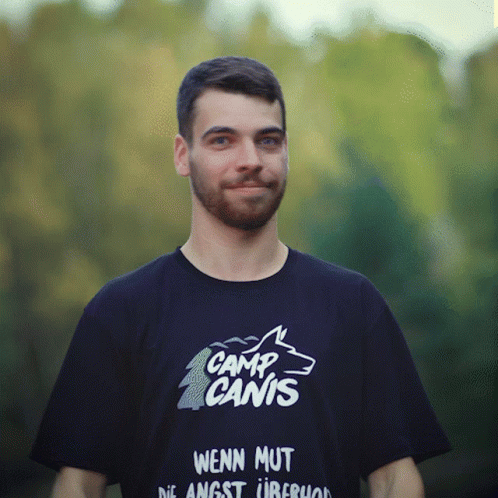 A Man Wearing A Shirt That Says Camp Canis On It GIF