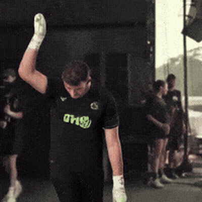A Man Wearing A Shirt That Says Dhs Is Raising His Hand In The Air GIF