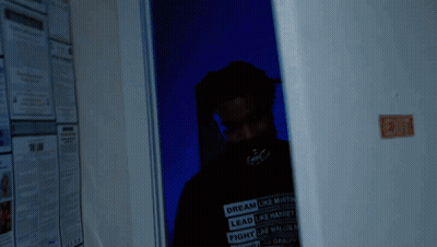A Man Wearing A Shirt That Says Dream Like Martin Is Standing In A Dark Room GIF
