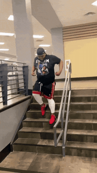 A Man Wearing A Shirt That Says Eminem Is Walking Down Stairs GIF