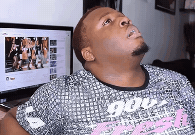 A Man Wearing A Shirt That Says ' God ' On It Looks Up At A Computer Screen GIF